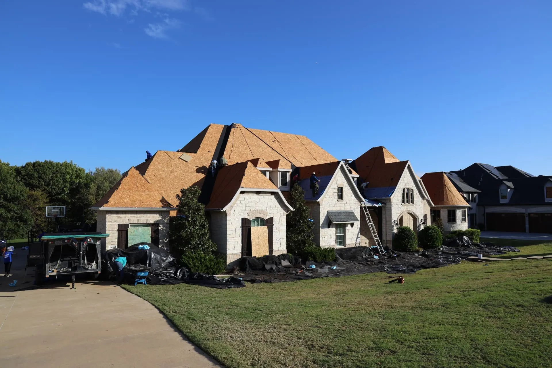 Driveway view of the Prosper home with exposed roof decking and crews at work