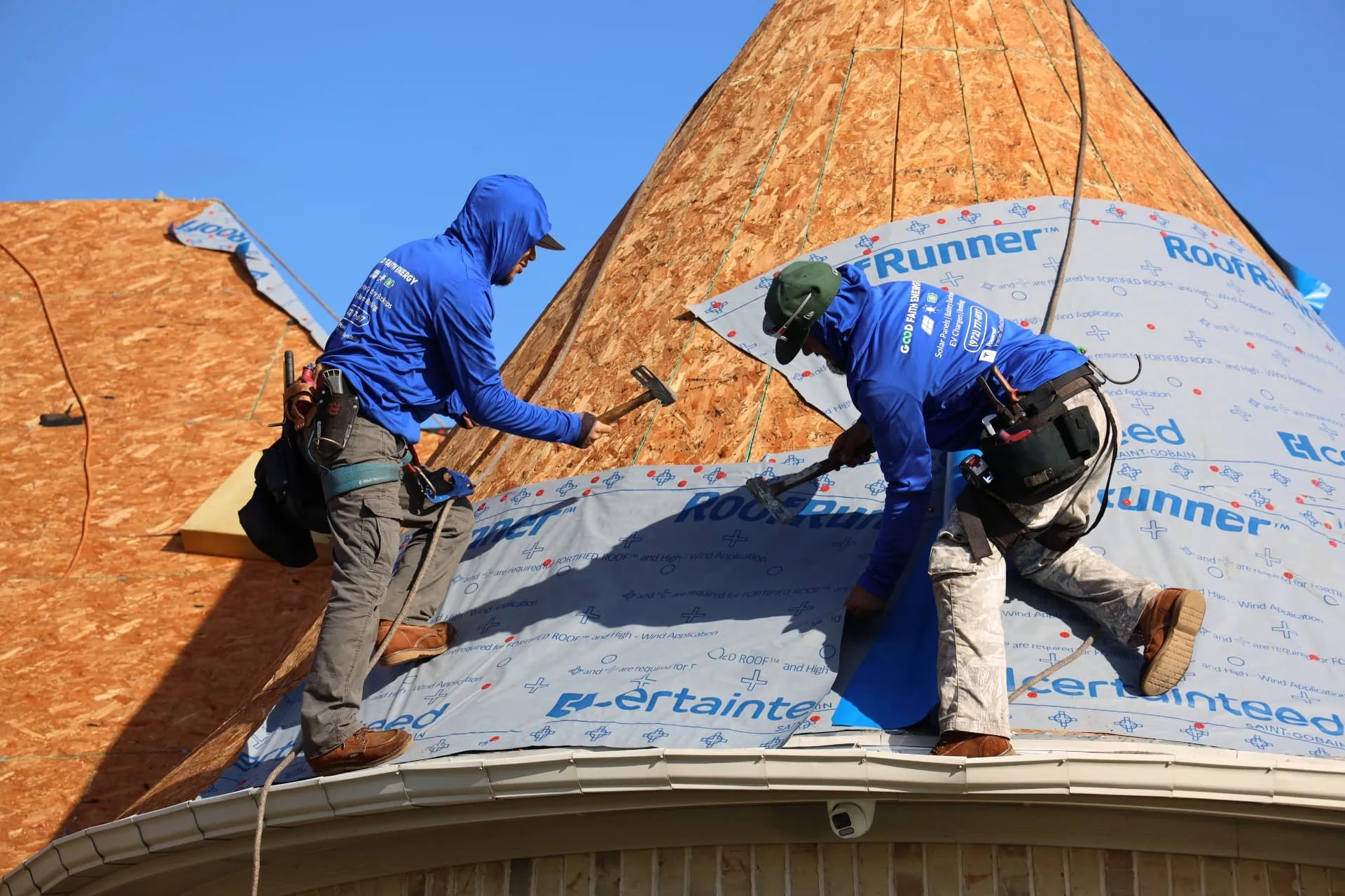 Two crew members fastening synthetic underlayment on the curved turret roof in Prosper