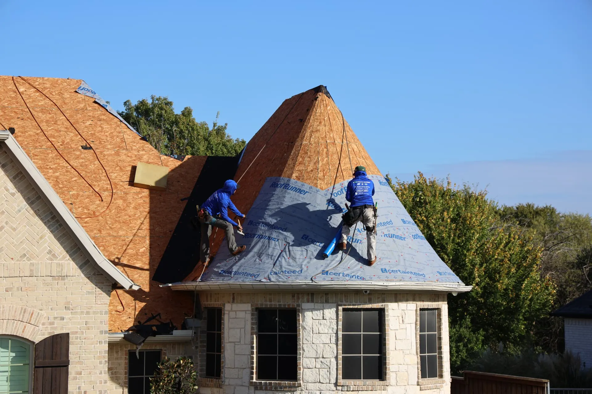 Exposed decking and roofing crew on the round turret of the Prosper home