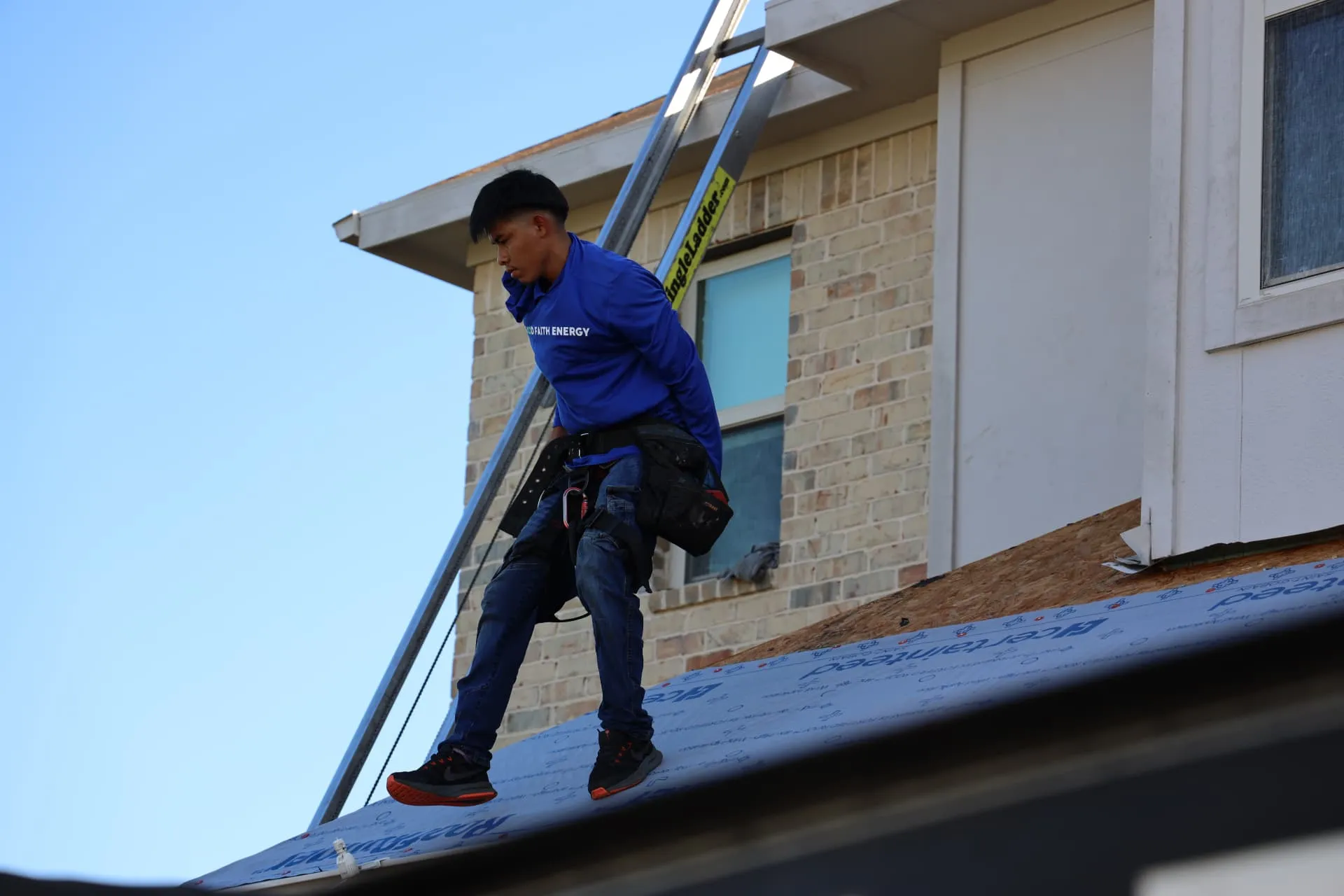 Good Faith Roofing installer carrying a roll beside a dormer on the Prosper roof