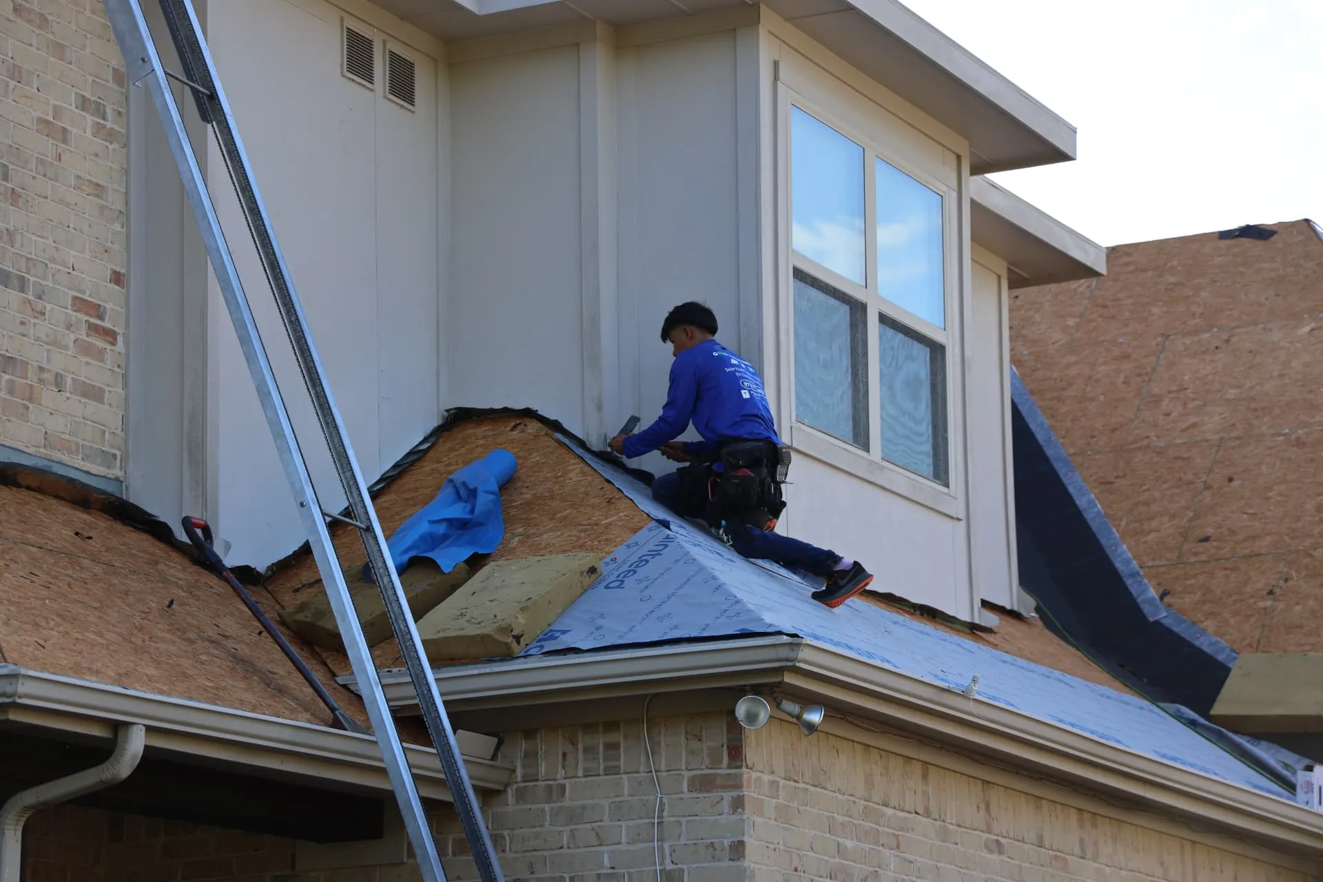 Roofing installer preparing underlayment at a dormer wall on the Prosper home