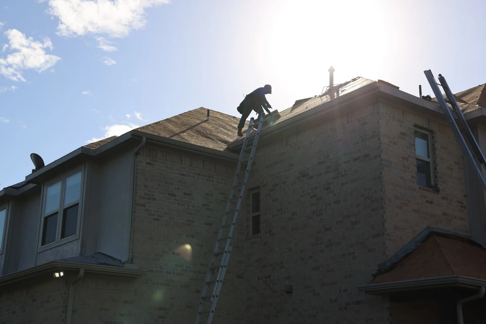 Crew member on the exposed roof deck above the stone rear elevation in Prosper