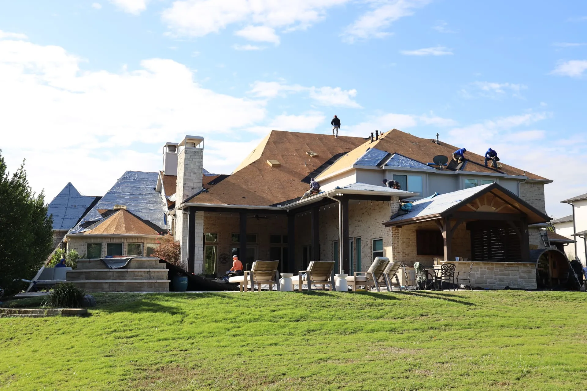 Rear of the Prosper home with crew members working across the exposed roof deck