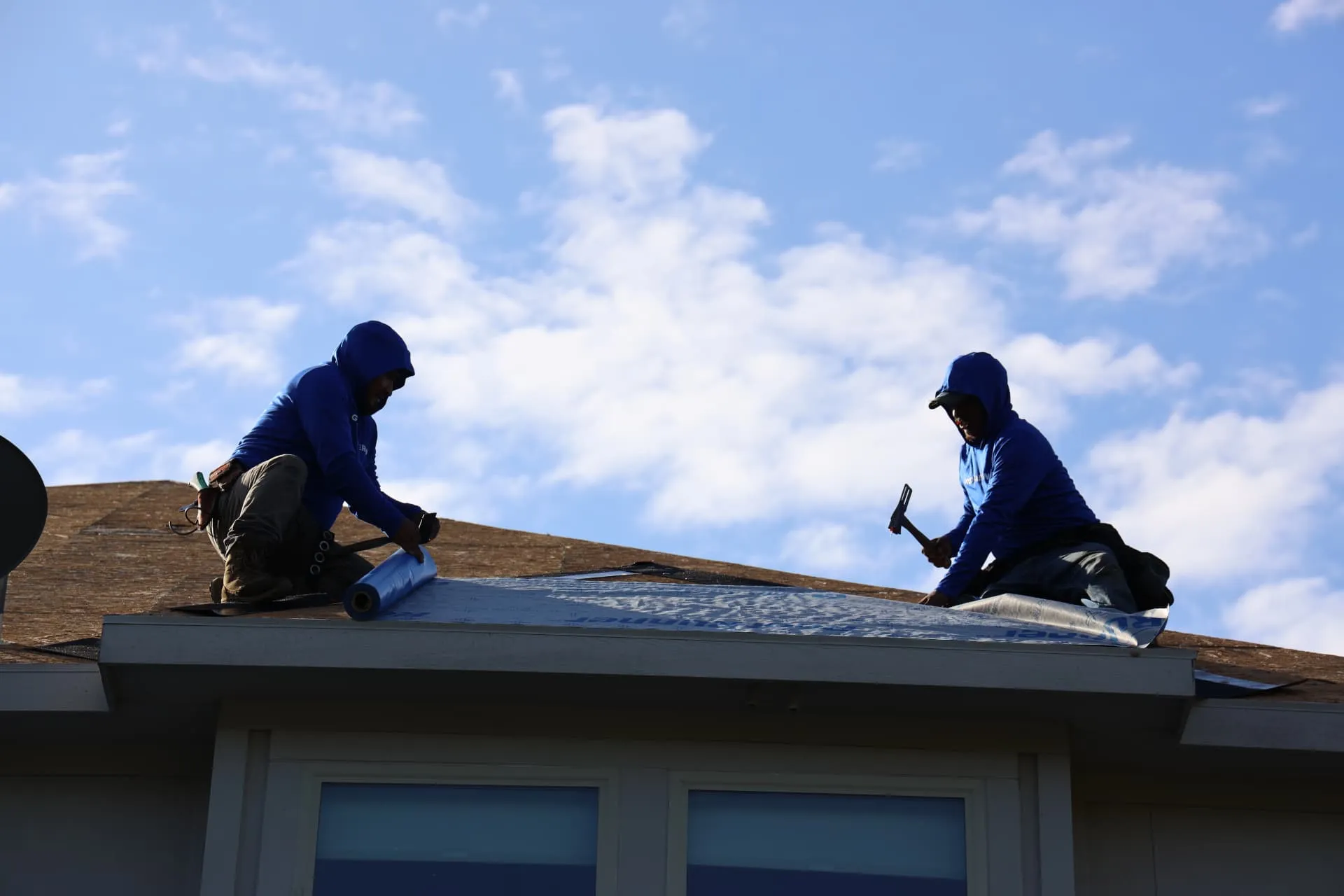 Two crew members working on the roof edge above a dormer in Prosper