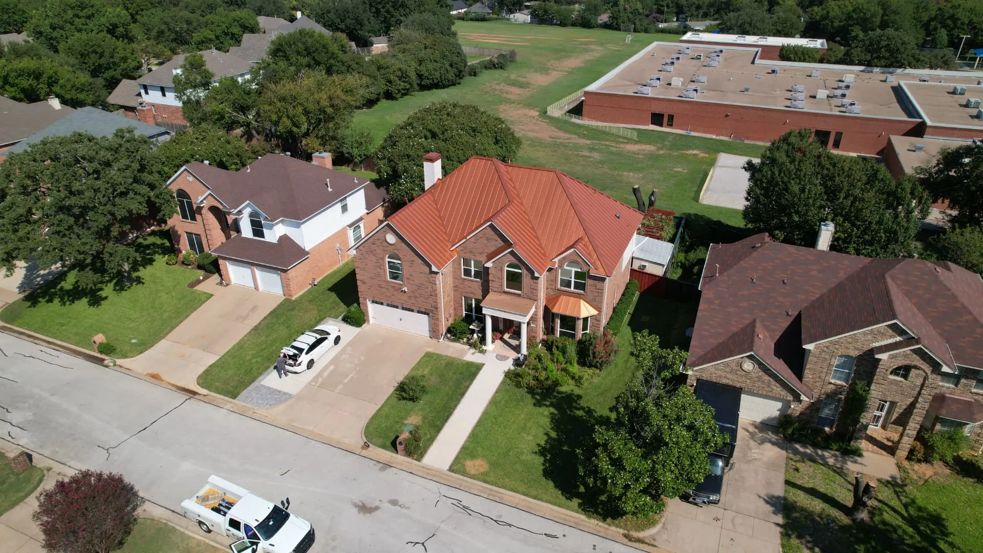 Drone view of a copper metal roof standing out in a North Texas neighborhood