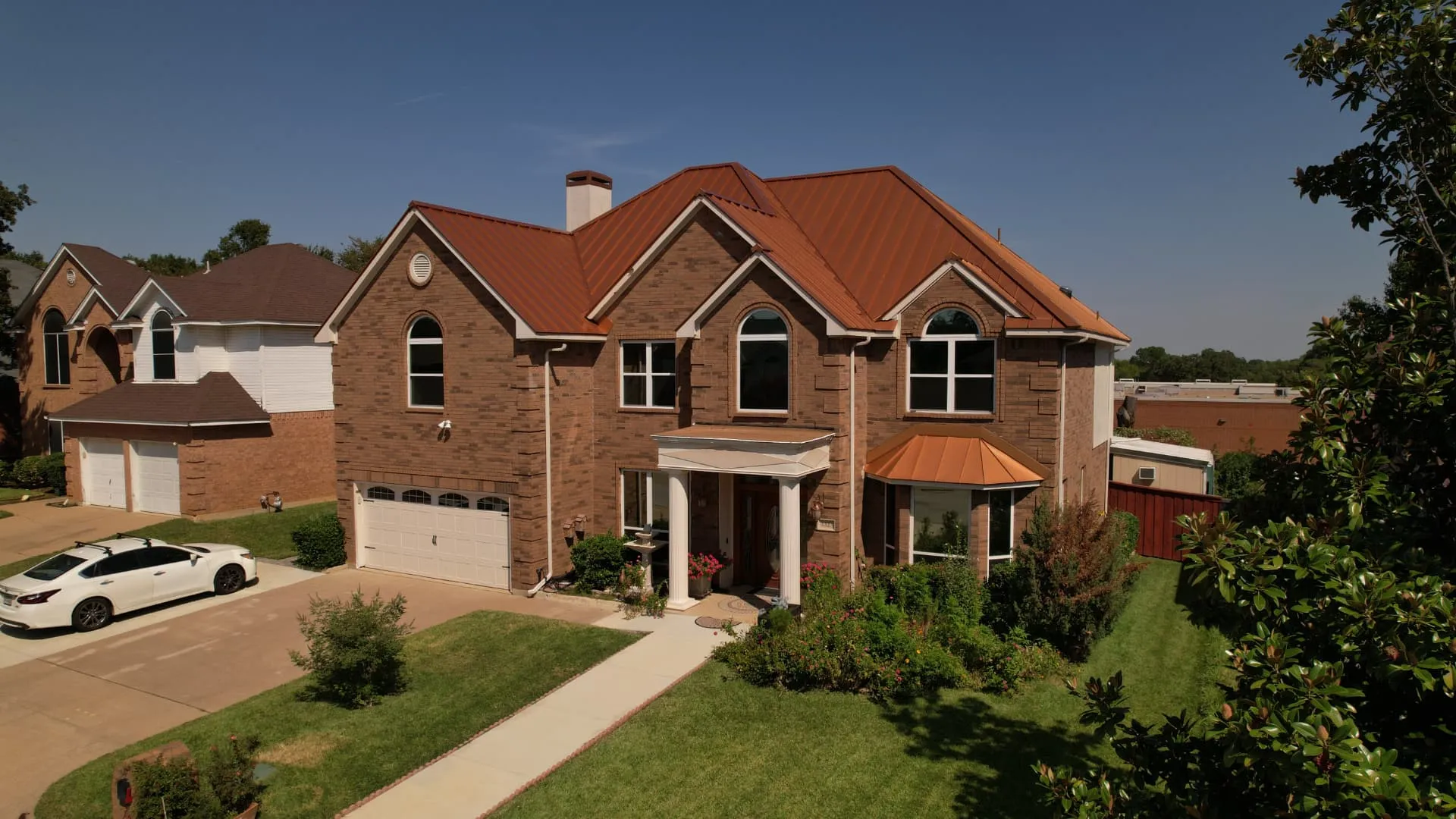 Front of a two story brick North Texas home with a finished copper standing seam metal roof