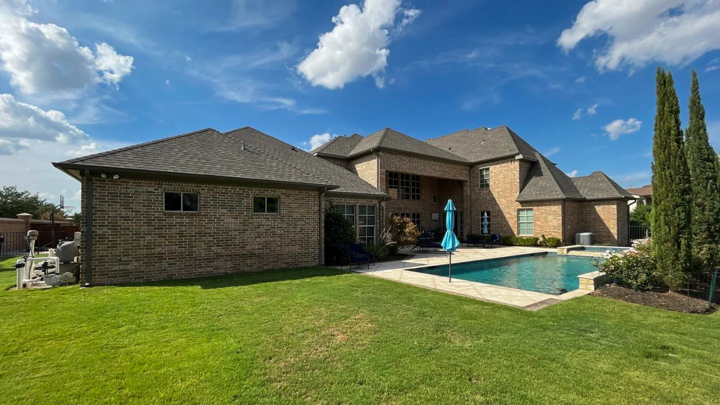 Arlington Texas brick home with a shingle roof under a mature front yard tree