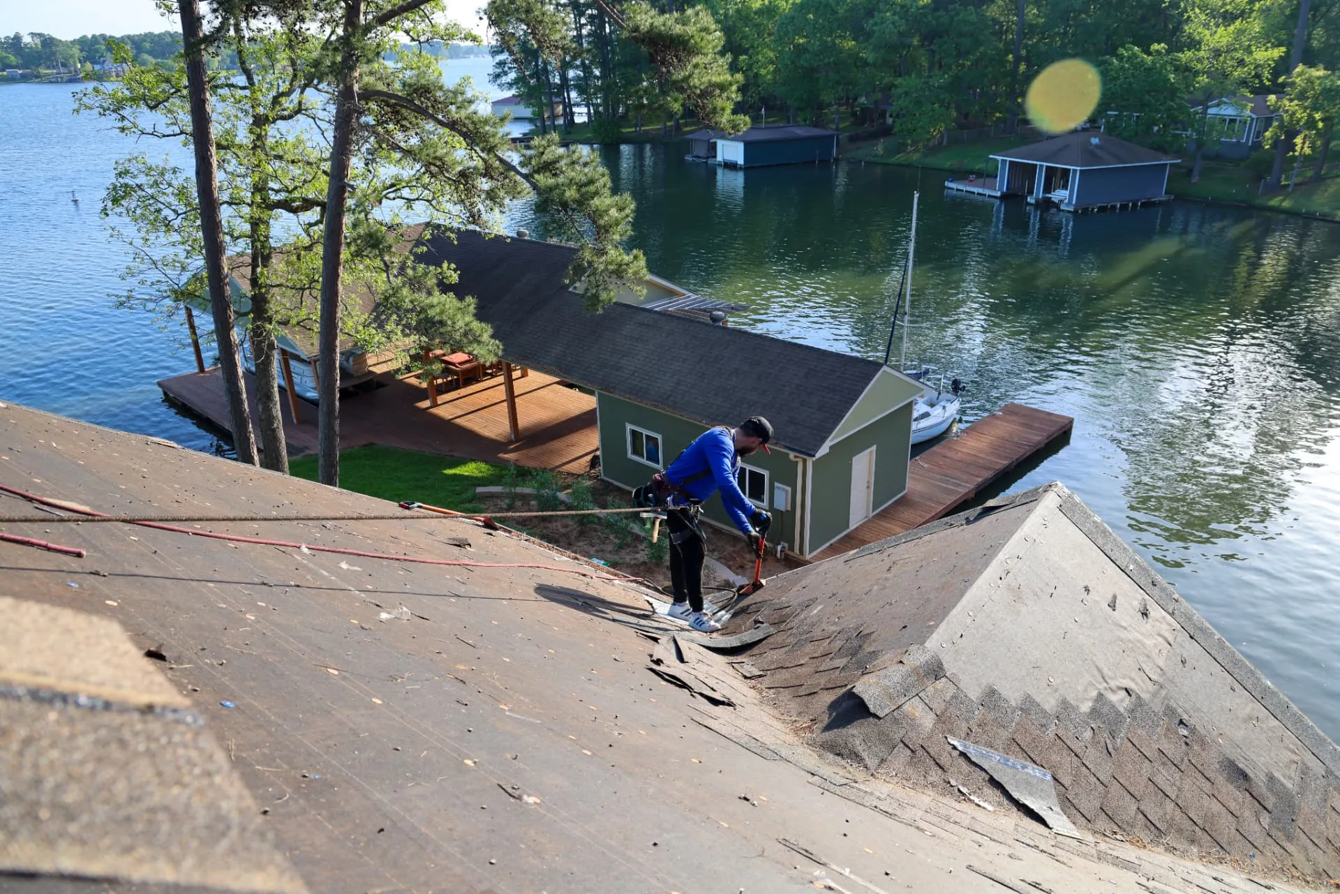 Good Faith Roofing installer on the exposed deck of a full roof replacement beside a lake
