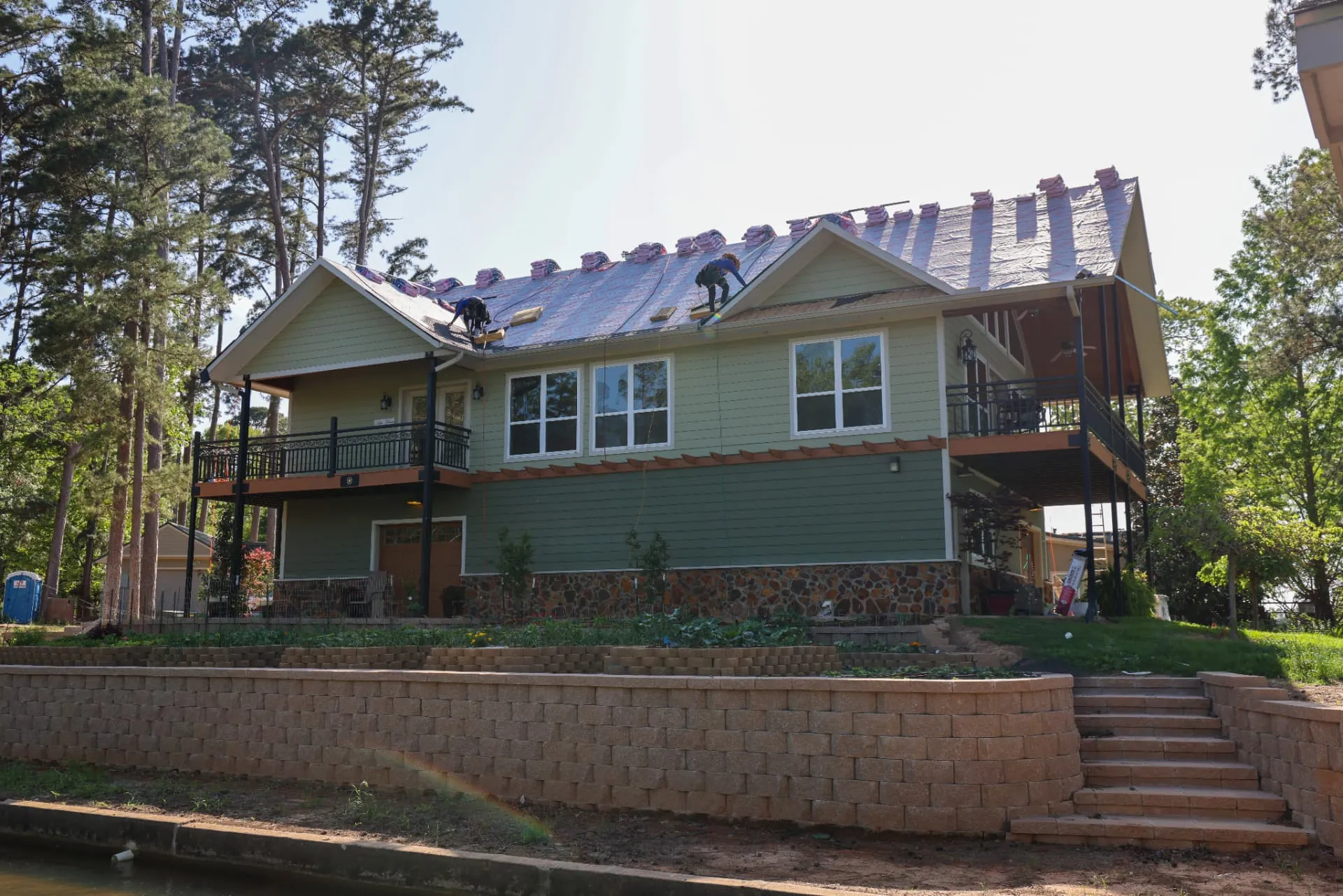 Good Faith Roofing crew replacing a storm-damaged roof on a North Texas lake house