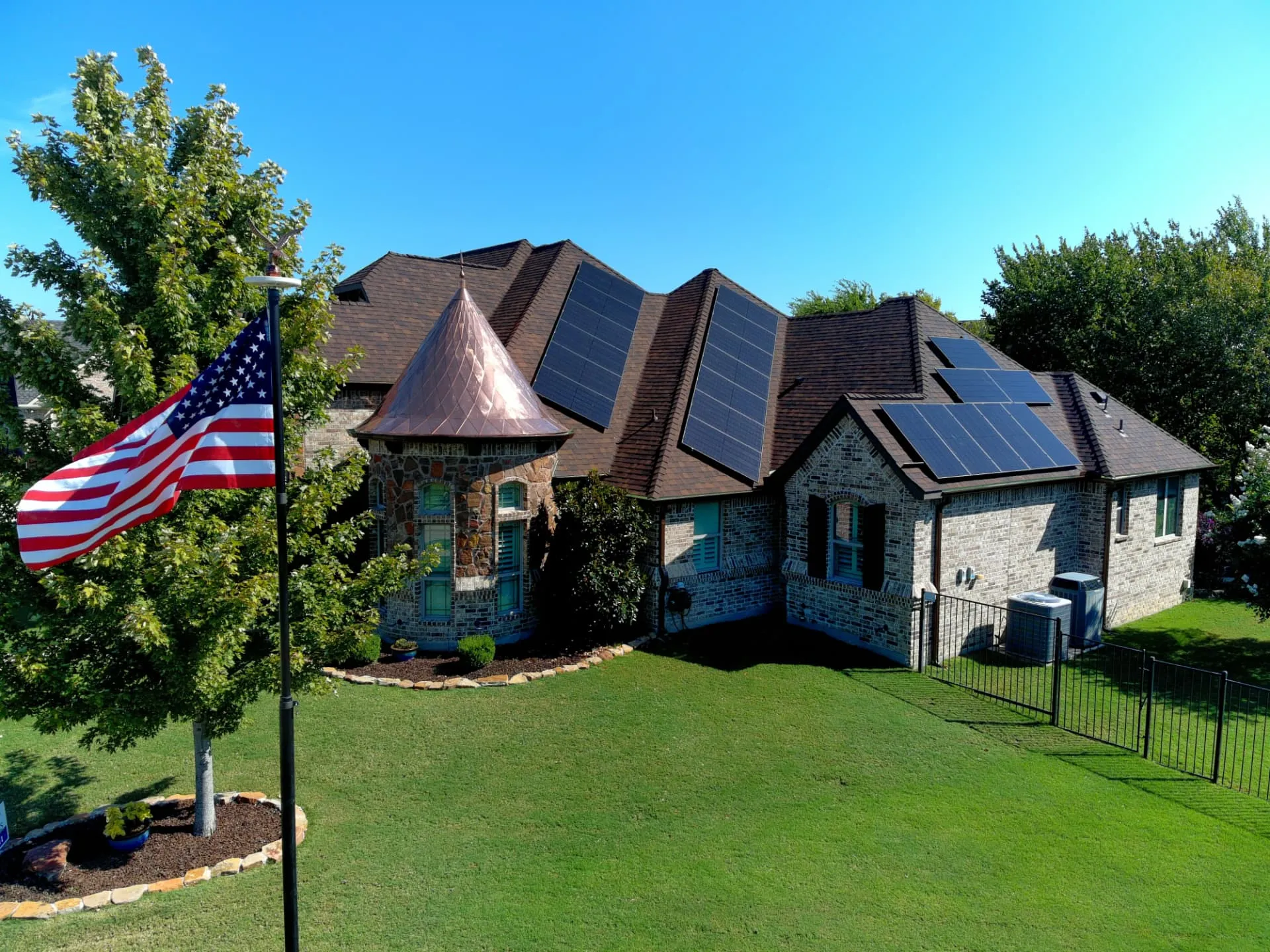 Technician spray-applying roof rejuvenation treatment to weathered asphalt shingles on a North Texas home