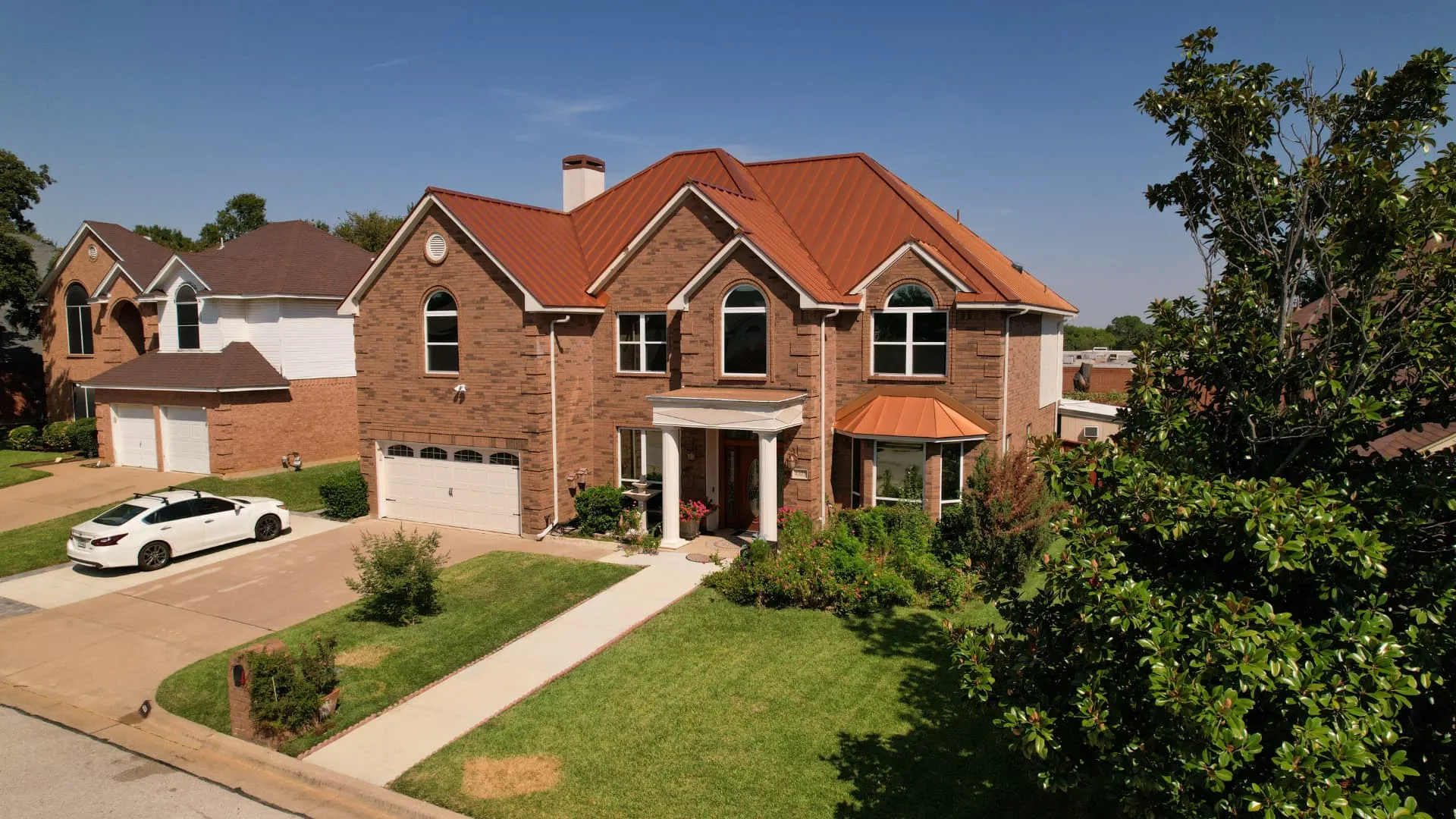 Two story North Texas brick home with a steep multi-gable roofline and finished metal roof