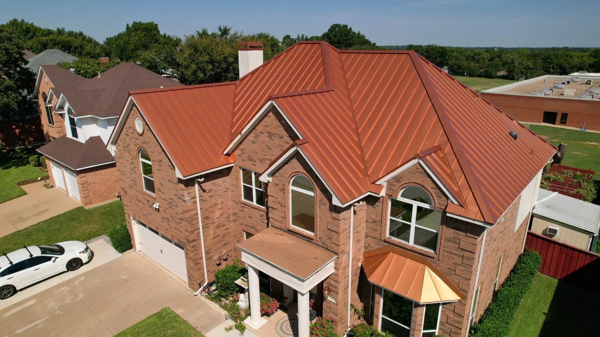 Copper-toned standing seam metal roof completed by Good Faith Roofing on a two story brick home in North Texas