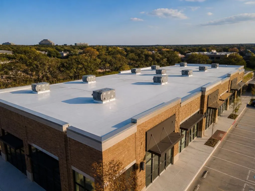 Aerial view of a newly installed white TPO flat roof on a Dallas retail strip