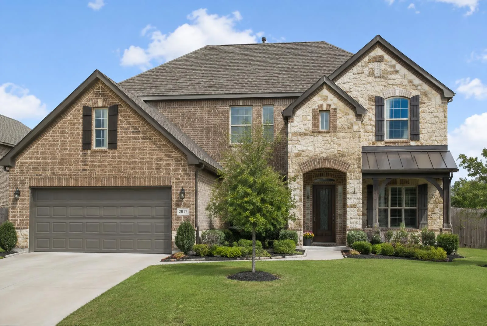 Completed architectural shingle roof on a two story brick and stone home in Flower Mound, Texas