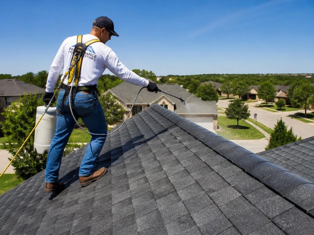 Technician spraying RoofMax rejuvenation treatment on a Plano shingle roof