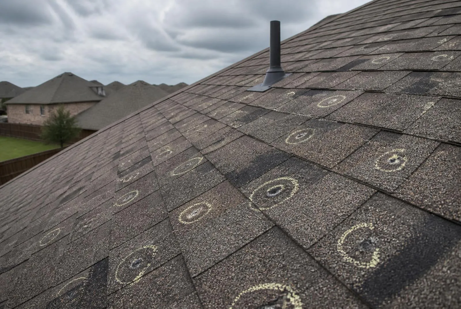 Hail-impacted asphalt shingles marked during a roof inspection in North Texas